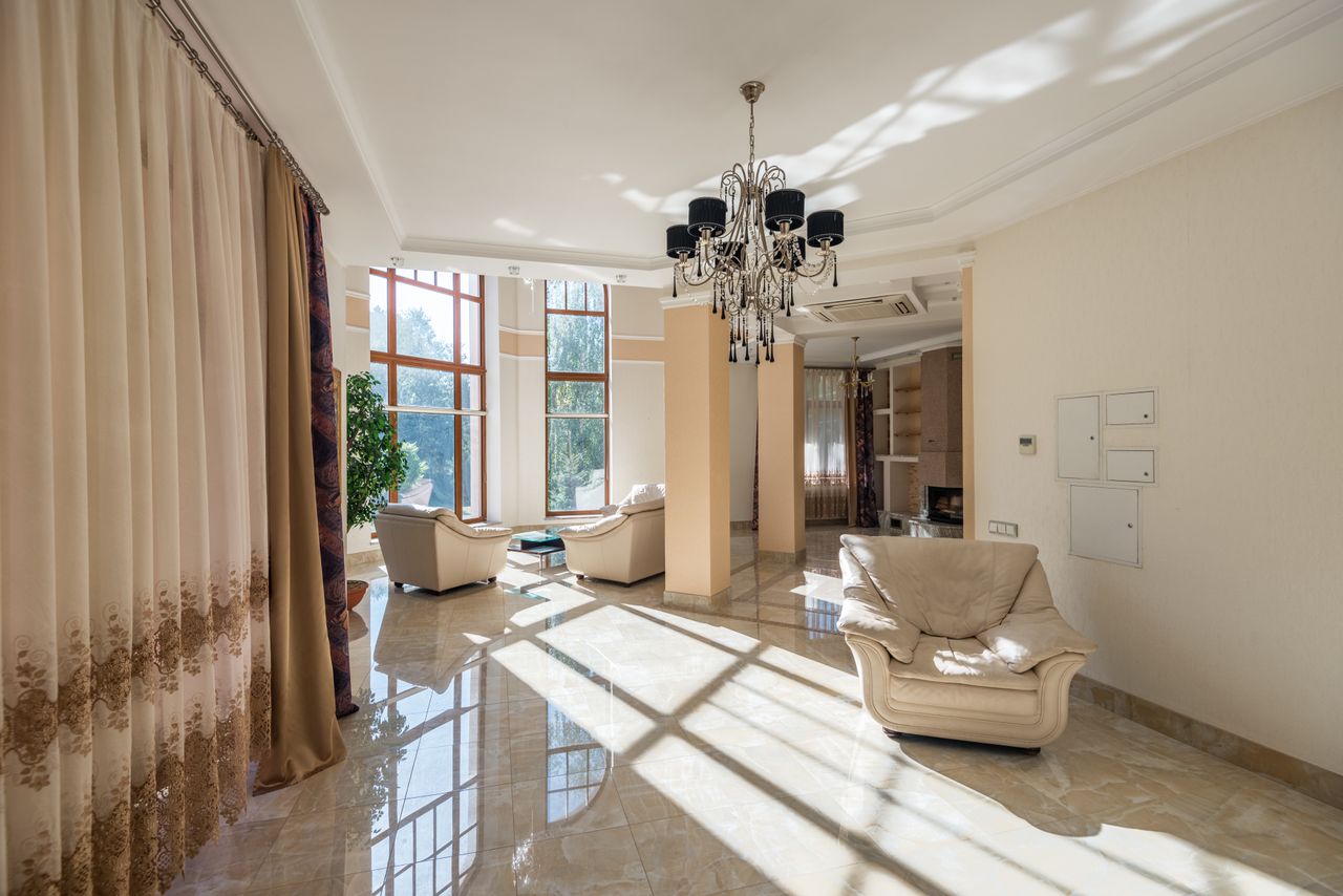 Luxurious living room featuring modern decor, large glass windows, and elegant chandelier.